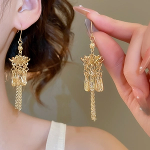Detail of vintage gold tassel bell earrings featuring intricate floral design and drop charms