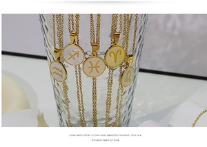 Λεπτομέρεια από μενταγιόν αστερισμών 18K χρυσού με λευκό κοχύλι μέσα σε γυάλινο μπολ