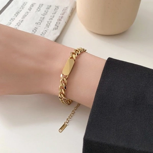 Close-up of golden Cuban chain bracelet with rectangular plaque and adjustable clasp