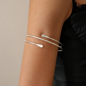 Detail of silver textured metal upper arm cuff with hammered finish on model