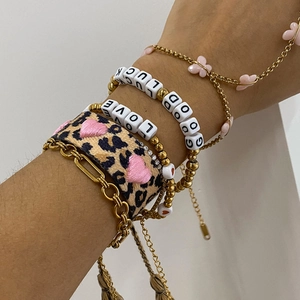 Detailed close-up of multilayer stacked bracelets with heart, leopard print, and letter beads