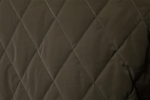 Macro view of diamond quilted fabric details on dark olive green jacket