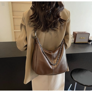 Brown leather Hobo bag featuring a stylish silver chain detail and sleek retro design
