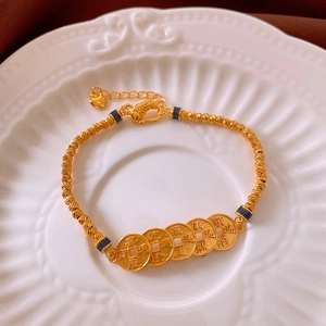 Detailed macro view of 18k gold plated five-emperor coins bracelet on ceramic tray