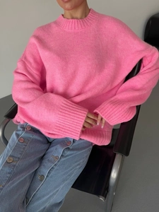 Detailed texture of pink oversized knit sweater paired with blue denim jeans on a model