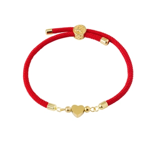 Macro shot of red Milan cord bracelet with 18K gold heart charm and adjustable tree clasp