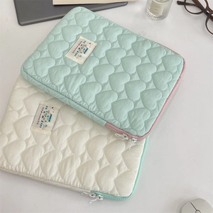 Detailed view of heart-quilted fabric texture on mint and cream laptop sleeves