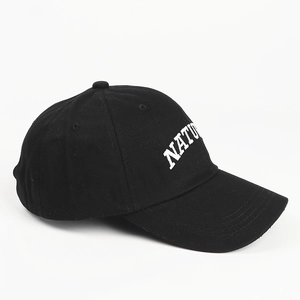 Close-up of white NATURE embroidery on a classic black cotton baseball cap