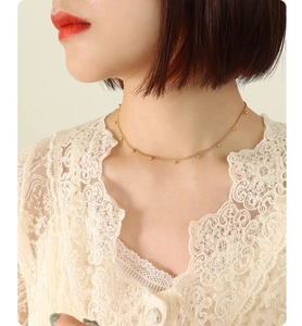 Close-up of golden beaded choker necklace on model neck showing elegant collarbone style