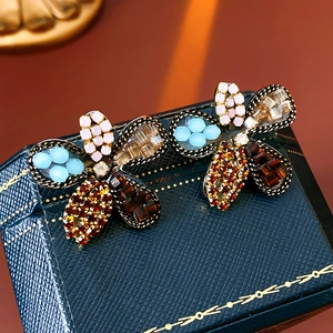 Macro detail of vintage floral stud earrings with colorful crystals and bronze alloy base