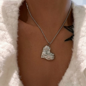 Detail showing high-polish silver heart pendant with textured ripple finish on rope chain