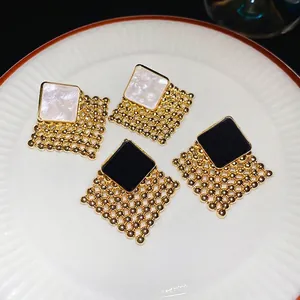 Vintage woven diamond earrings in white marble and black finish on white ceramic plate