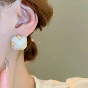 Primo piano di orecchini a perno geometrici in oro e bianco indossati su un orecchio