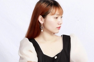 Detail showing silver heart hoop earrings with pearl charms on a model's ear