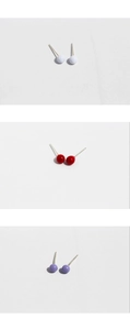 Detailed view of colorful round ball stud earrings in vibrant red, white, and purple finishes