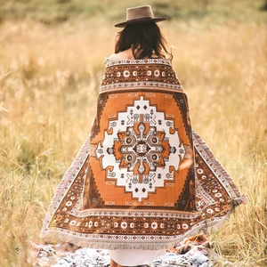 Close-up of bohemian picnic blanket with geometric patterns and fringe edges in autumn field