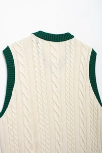 Detailed macro view of cream-white cable knit texture with green V-neck ribbed trim