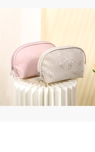Detail of pink and beige floral jacquard PU makeup bags on elegant paper art display