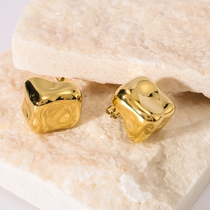 Irregular hollow square gold earrings in stainless steel on white stone blocks