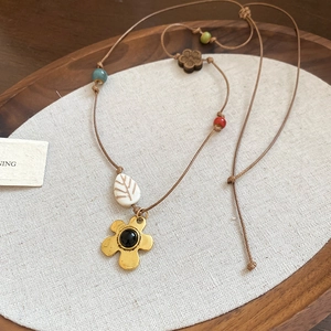 Vue détaillée du collier ethnique avec fleur dorée et pendentif feuille en céramique