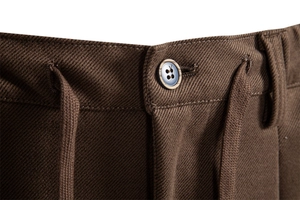 Close-up of thick brown twill fabric with amber button and cotton drawstring