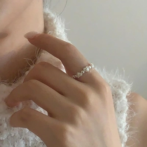 Detail of S925 sterling silver heart-shaped band ring worn on finger with soft lighting