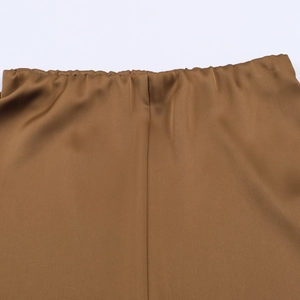 Detail view of brown satin skirt featuring an elastic waistband and smooth silk texture