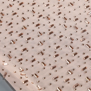 Détail des strass rose doré et perles de cristal sur un tissu en maille délicate