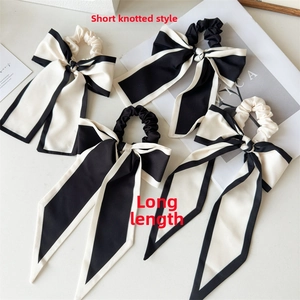 Detail view of black and white satin bow scrunchies in short knotted and long ribbon styles