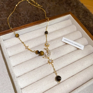 Macro detail of crescent moon necklace with tiger eye beads in a velvet jewelry box