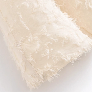 Dettaglio ravvicinato della gonna svasata color bianco crema con frange tessute