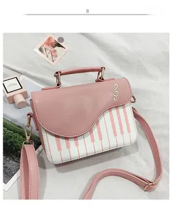 Detail of white and pink piano-themed crossbody bag with embroidered treble clef motif