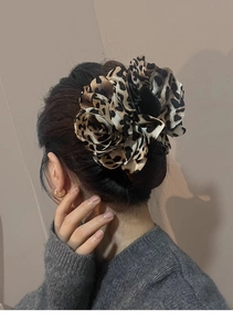 Close-up of leopard print flower hair claw clip worn by a model for elegant styling