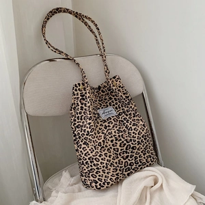 Close-up of leopard print canvas tote bag with woven brand label on white metal chair