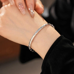 Detailed view of silver arrow pattern bangle with polished geometric scale texture