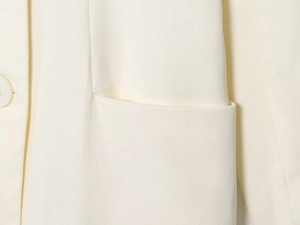 Close-up of double-breasted white blazer showing twill fabric texture and pocket stitching