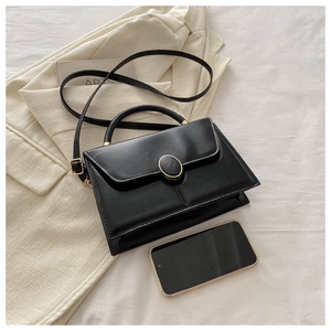 Détail du sac à main noir en simili cuir avec boucle dorée et smartphone de référence