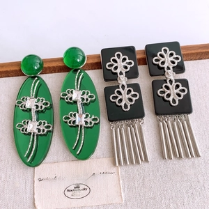 Détail de boucles d'oreilles vintage en résine avec pendentifs ovales verts et franges noires