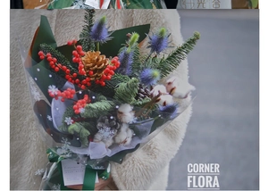 Close-up of Christmas bouquet with red berries, pine cones, and snowflake wrapping