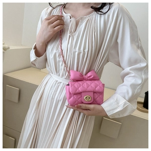 Detail of a pink mini crossbody bag with a large bow and classic quilted texture