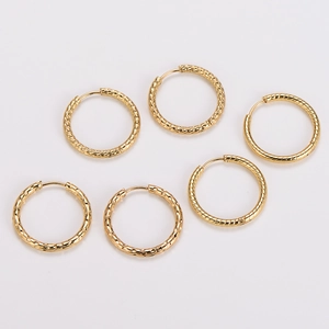 Macro detail of gold-plated hoop earrings with hammered and spiral twisted textures
