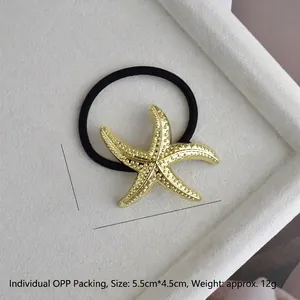 Macro detail of golden starfish hair tie with embossed dots on a white textured tray