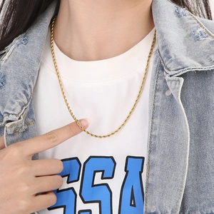 Close-up of a gold twisted rope chain necklace worn by a model in casual attire