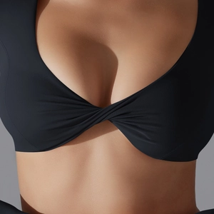 Dettaglio top yoga nero a maniche lunghe con design a torsione frontale e scollo a V
