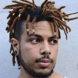 Close-up of a man wearing multiple silver alloy spiral hair rings and dreadlock accessories
