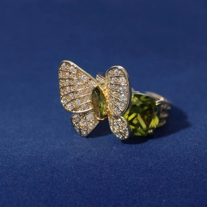 Macro shot of gold butterfly ring with green gemstone and sparkling zircons