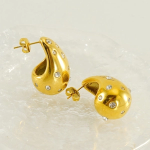 Détail des boucles d'oreilles gouttes dorées bombées avec des zircons incrustés