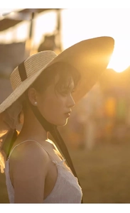 Close-up of wide brim straw hat with black ribbon in warm outdoor sunset light