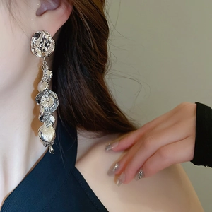 Gros plan de boucles d'oreilles pendantes en métal liquide argenté portées par un mannequin