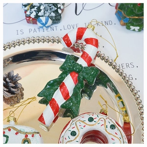 Close-up of candy cane Christmas ornament with red stripes and green bow on metal tray